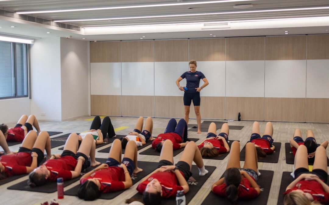 Group of teenagers engaging in a mindful breathing exercise during a yoga class at Kellett International School with Rowena Hunt